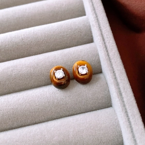 Close-up of vintage oval tiger eye stud earrings with zircon inlay in a grey jewelry box