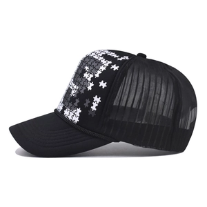 Detail of black trucker hat showing puzzle print, breathable mesh, and braided rope accent