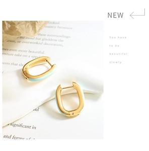 Close-up of elegant gold U-shaped earrings with light blue enamel and a polished finish