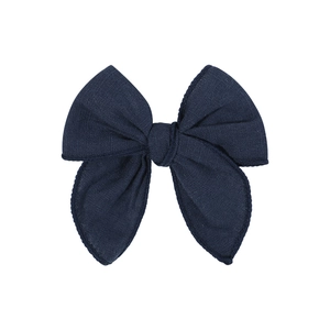 Detailed macro view of dark blue fabric bow hair clip with fine cotton linen texture