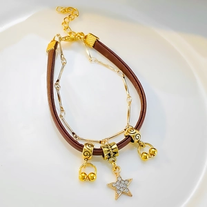 Macro detail of multilayer leather bracelet featuring gold star charm and beads