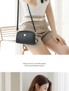 Detail of pebbled leather texture on black mini crossbody bag with gold dual zippers