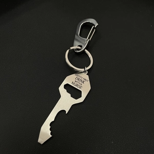 Silver metal keychain tool with Safety First engraving on a dark background