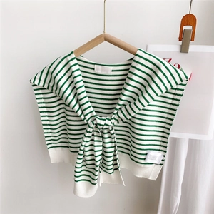 Close-up of green and white striped knit shawl with a knotted tie design on a hanger