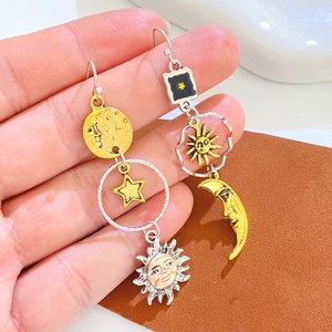 Close-up of vintage celestial earrings featuring moon, sun, and star charms in mixed metal
