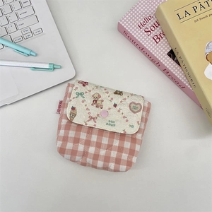 Detail of pink plaid quilted storage pouch with button closure on a desk setup