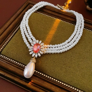 Vue détaillée du collier de perles à trois rangs avec fleur de rubis et perle goutte