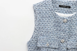 Close-up of blue and white textured tweed vest featuring a silver woven metal button
