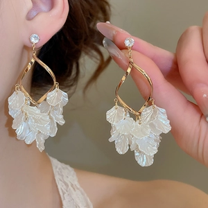 Detail of gold petal tassel earrings with white resin flowers and zircon stud