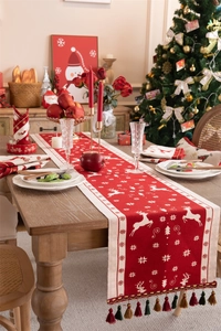 Detail of red Christmas table runner with white reindeer patterns and festive tassels