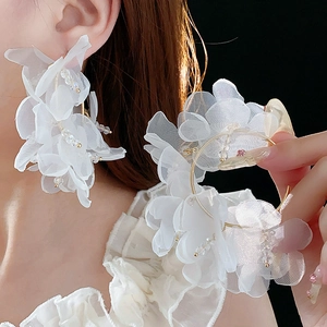 Détail de boucles d'oreilles fleur en maille blanche avec créole dorée sur modèle