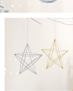 Detail of glittered gold and silver star ornaments hanging on a Christmas tree branch