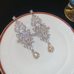 Exquisite silver drop earrings with sparkling rhinestones on a white ceramic plate