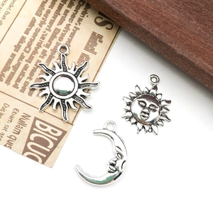 Macro detail of sun and moon face charms on vintage newspaper and wood background