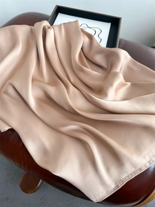 Detail of nude pink silk scarf showing smooth texture and glossy drapes on leather