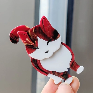 Close-up of cute calico cat acrylic brooch with marble texture and white patches
