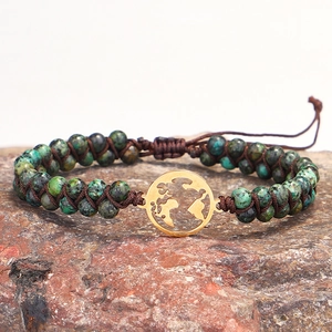 Handmade African turquoise beaded bracelet with golden world map charm on rock