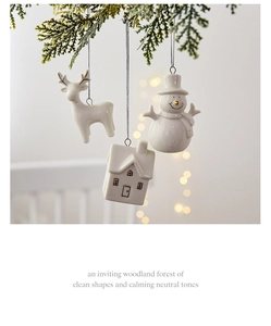 Ceramic Christmas tree ornaments with reindeer and snowman shapes hanging on pine branches