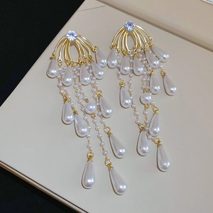Detailed macro view of gold tassel earrings with teardrop pearls and blue stones