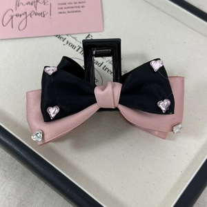 Detailed view of pink and black ribbon bow hair claw clip with sparkling heart rhinestones
