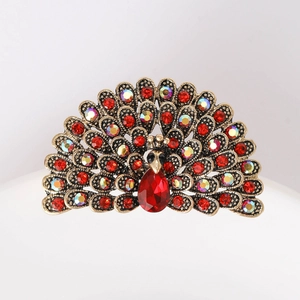 Detailed close-up of a golden peacock brooch with sparkling red and iridescent crystals