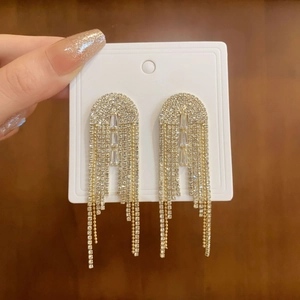 Detail of long tassel earrings with sparkling rhinestones in a golden finish metal