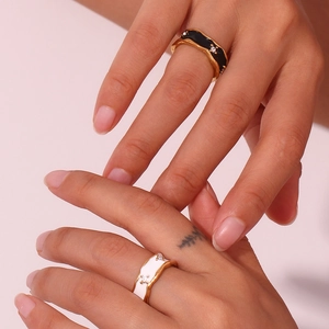 Detail of model wearing vintage 18K gold plated rings with black and white enamel and crystals