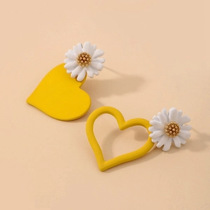 Detailed macro view of asymmetric daisy and heart earrings in warm yellow and white