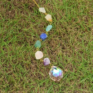 Détail de sept pierres naturelles de chakra et une boule de cristal à facettes pour jardin