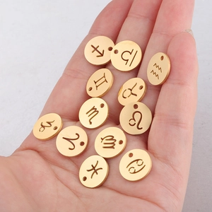 Hand holding twelve golden circular zodiac charms made of mirror-finish titanium steel