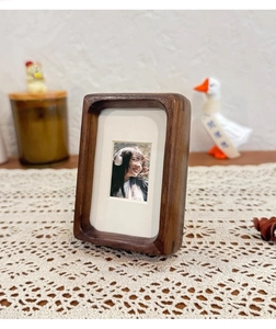 Detail of walnut wood magnetic photo frame with round corners on white lace tablecloth