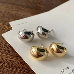 Dettaglio di orecchini a perno curvi minimalisti in finitura oro e argento lucido