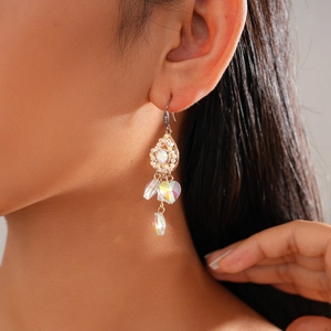 Close-up of vintage gold earrings with heart-shaped crystals and zircon water drops