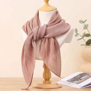 Gros plan d'un foulard carré rose froissé noué sur un mannequin au décor naturel