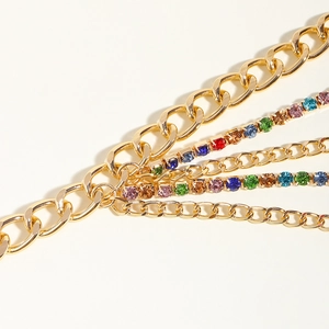 Détail macro d'une chaîne gourmette dorée multicouche avec strass colorés brillants