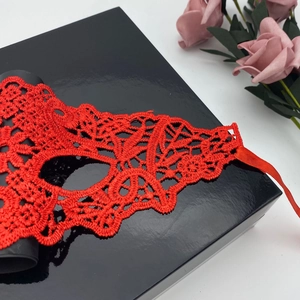 Detailed macro view of the intricate red lace texture and satin ribbon on the mask