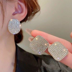 Close-up of a model wearing a luxurious gold square earring paved with shimmering crystals