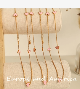 Detailed view of pink enamel heart pendants on a gold chain necklace for women