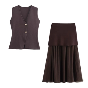 Detalle de chaleco de punto con cuello en V, botones dorados y falda midi plisada