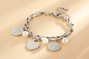 Détail d'un bracelet à breloques argenté avec perles, pendentif cœur et médailles saintes