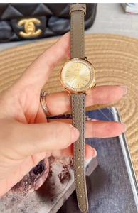 Detail of luxury woman's quartz watch featuring rhinestone bezel and grey leather strap