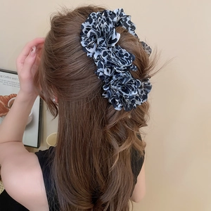 Detailed close-up of a large leopard print chiffon scrunchie with elegant pleated fabric texture