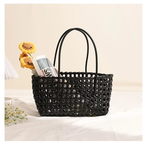 Close-up of black hollow-out woven plastic tote bag with sunflowers for beach vacation