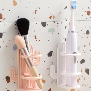 Pink and white cactus wall-mounted toothbrush holders on a terrazzo wall background