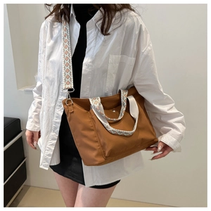 Detail of a brown nylon tote bag featuring a stylish ethnic pattern wide shoulder strap
