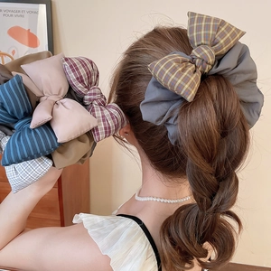 Detailed view of checkered fabric scrunchie with large bow on a braided hairstyle