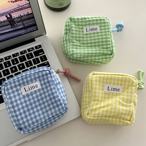 Detailed view of three checkered canvas pouches in blue, green, and yellow on a desk