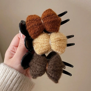 Detailed view of knitted bow hair clips in brown, beige, and grey with claw grips