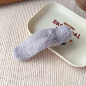 Detailed macro view of a lavender plush faux fur hair clip on a soft textured background