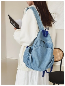 Side view of woman wearing a small vintage blue denim backpack in a minimalist room
